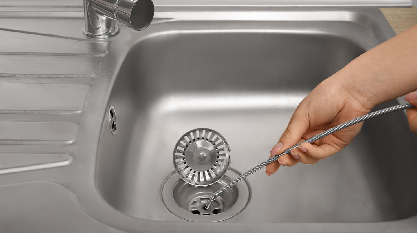 Section de tuyau de drain résidentiel ouverte montrant une accumulation épaisse de graisse solidifiée jaunâtre réduisant le diamètre intérieur